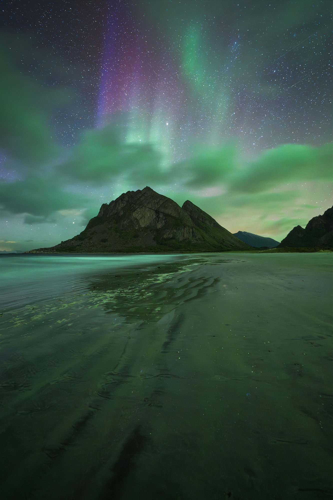 Northern lights landscape photography at Bøsanden Beach in Steigen, Norway, captured at night with aurora borealis dancing above the Arctic coastline.