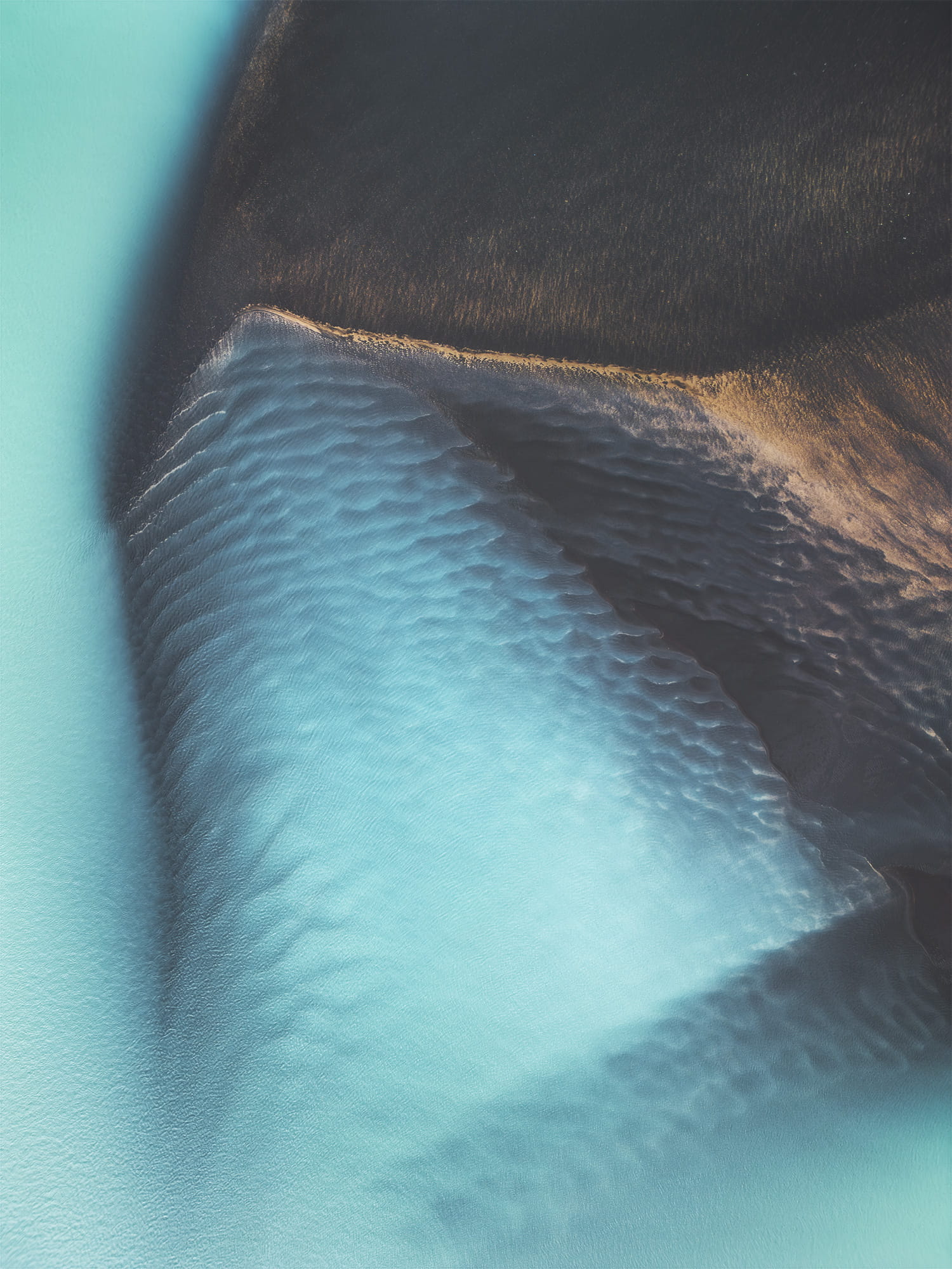 Landscape photography captured by drone above braided rivers in the Selfoss region of southern Iceland, showcasing abstract blue water channels from a top-down aerial view.