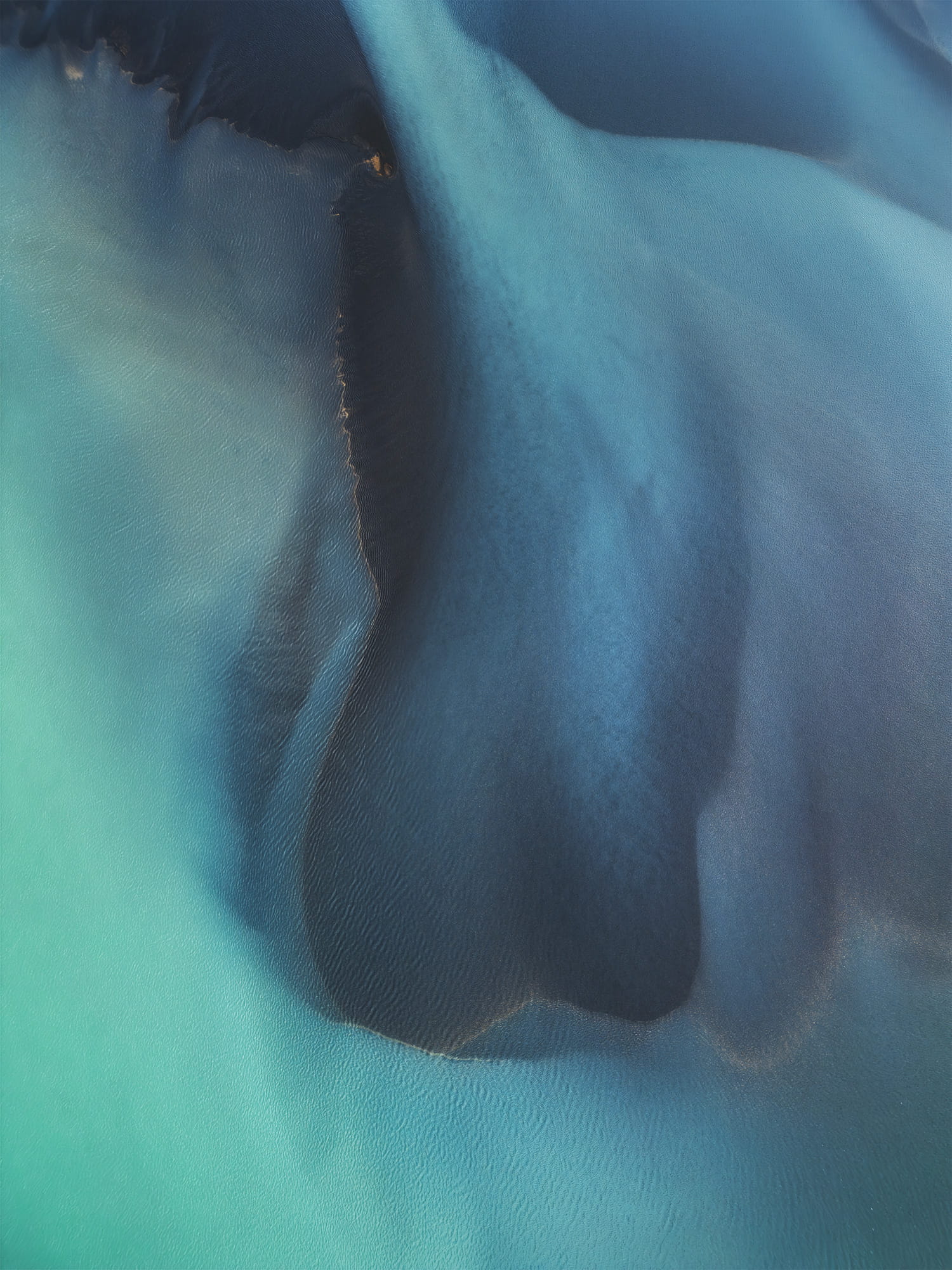 Drone landscape photography of braided rivers near Selfoss in southern Iceland, featuring a vivid blue river weaving through volcanic terrain seen from an aerial perspective.