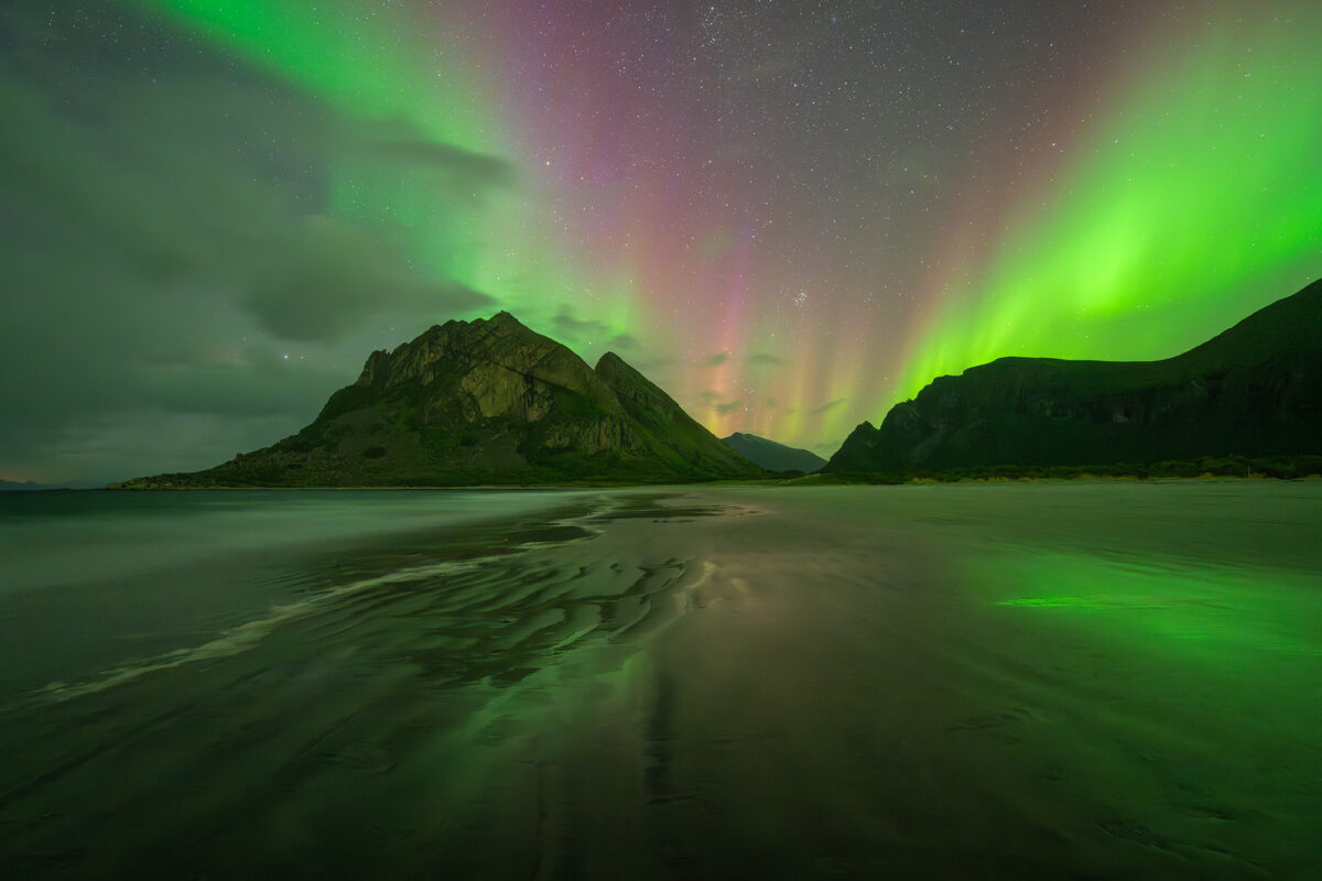 Amazing northern lights landscape photography at Bøsanden Beach in Steigen, Norway, captured at night with aurora borealis dancing above the Arctic coastline.