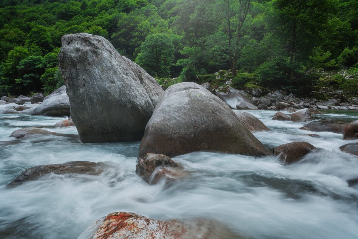 Long exposure river in Val Verzasca, Ticino, Switzerland with large boulders and milky water, alpine landscape photography.