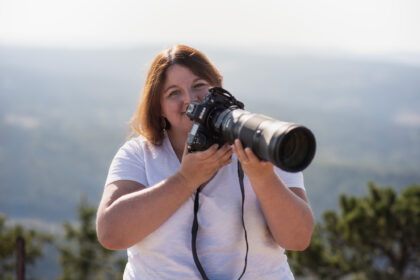 Swiss landscape photographer Jennifer Esseiva holding a Nikon Z8 with a NIKKOR Z 180-600mm telephoto lens while photographing outdoors in Switzerland.