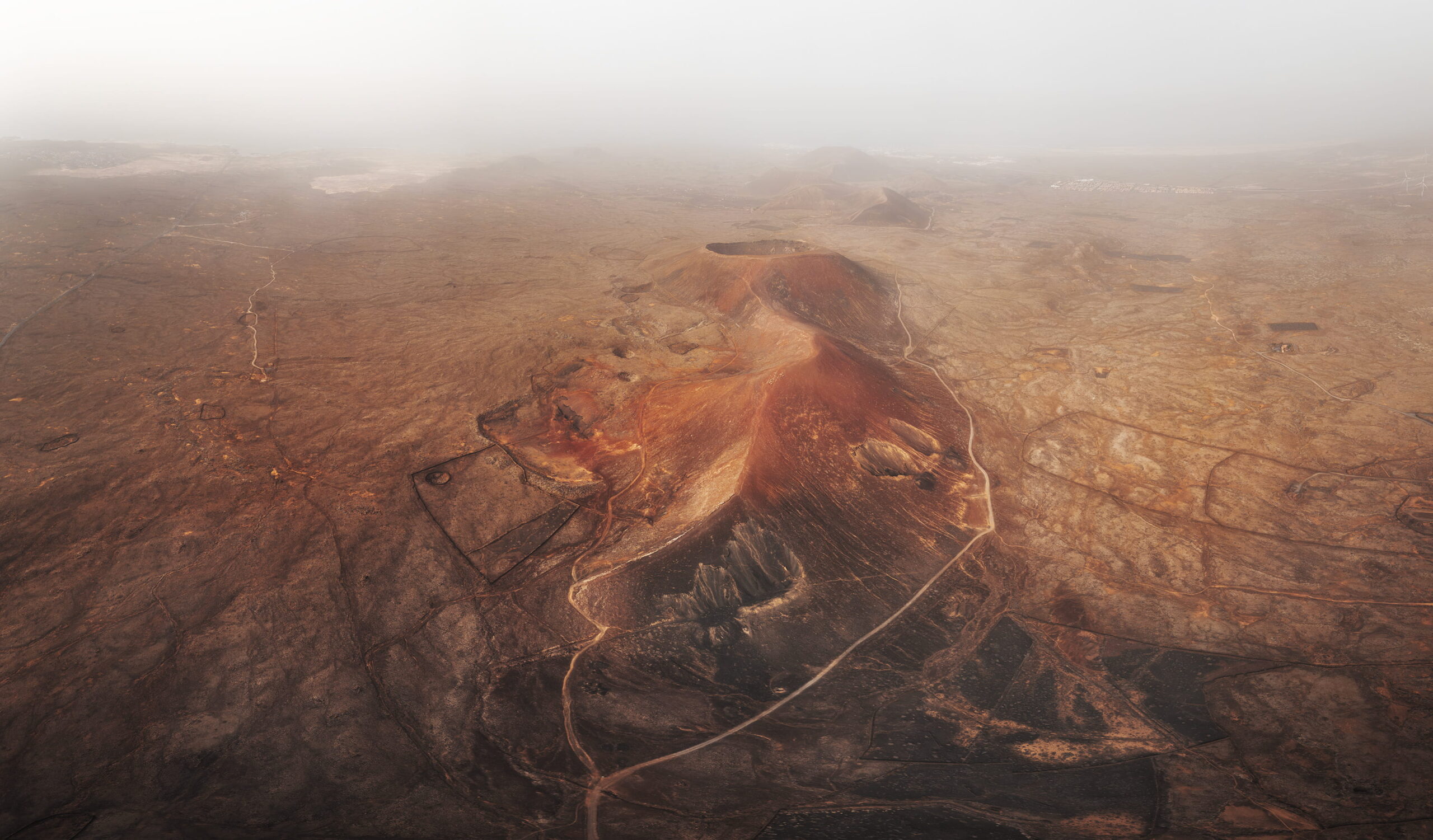 Aerial panorama of Calderón Hondo volcano in Fuerteventura, Canary Islands, viewed from the south through the warm haze of a Calima dust storm.