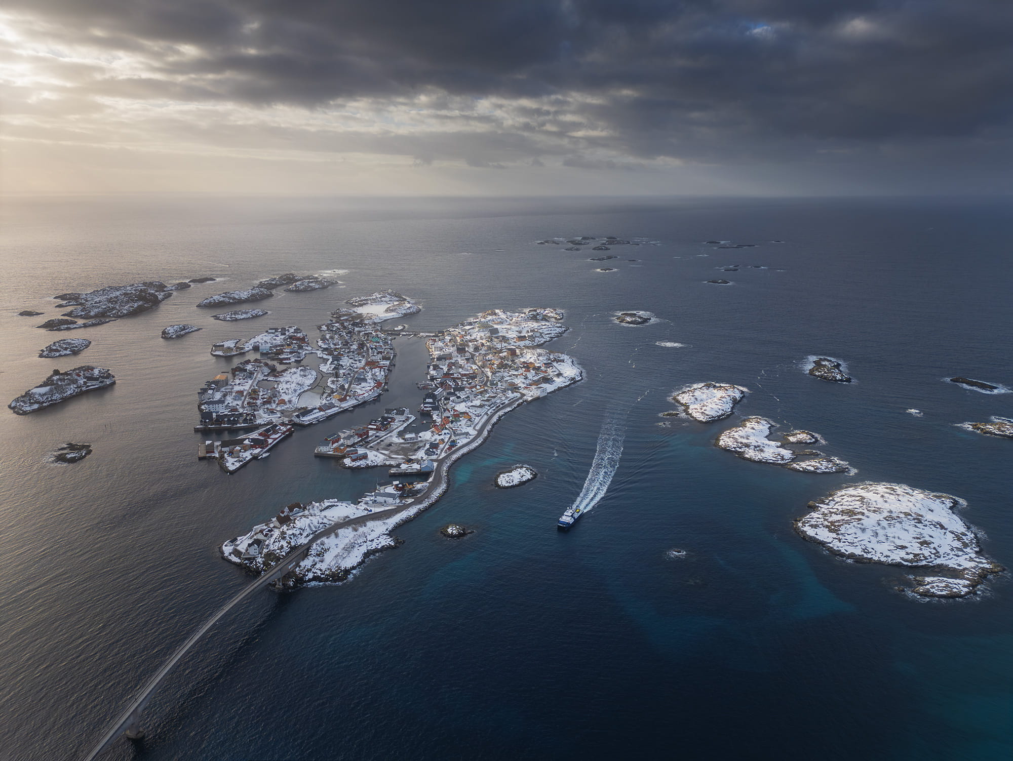 Drone view of Henningsvær in winter, with the snow-covered fishing village and small islands surrounded by the Norwegian Sea in the Lofoten Islands, Norway.