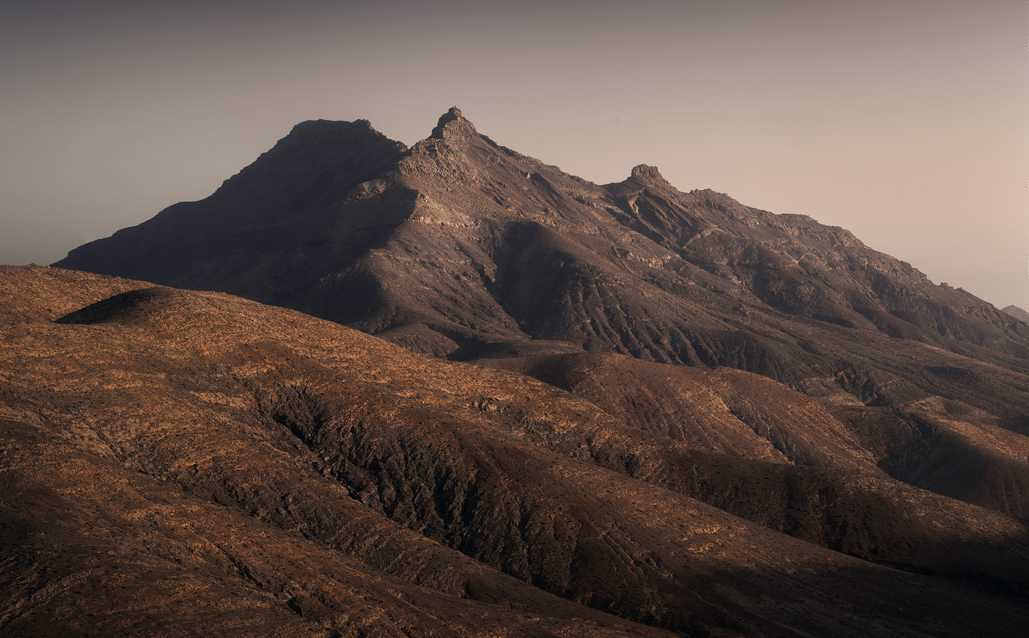 Volcanic mountain landscape seen from Sicasumbre viewpoint in Fuerteventura, illuminated by warm golden light across the rugged peaks of the Canary Islands.